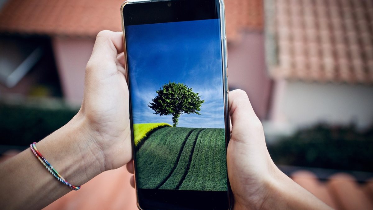 动漫壁纸 App 主界面在手机屏幕上展示，深色背景中排列着多张动漫角色与场景壁纸缩略图，顶部搜索栏与分类标签清晰可见，整体氛围安静克制